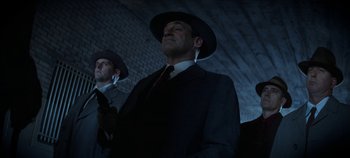 Movie still from “No Sudden Move” (2021), directed by Steven Soderbergh – A man in a suit and a man in a hat; Medium shot, Low angle