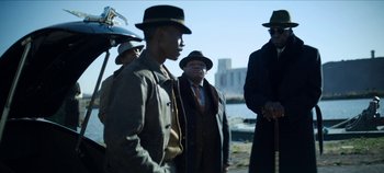 Movie still from “No Sudden Move” (2021), directed by Steven Soderbergh – A group of men standing next to each other on a beach; Medium shot, Low angle