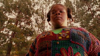 Movie still from “Norbit” (2007), directed by Brian Robbins – A young girl wearing a colorful sweater standing in front of a tree; Close Up shot, Low angle