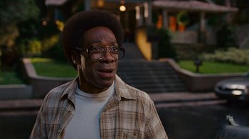 Movie still from “Norbit” (2007), directed by Brian Robbins – A man in a plaid shirt is standing in front of stairs; Close Up shot, Over the shoulder angle