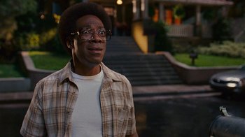 Movie still from “Norbit” (2007), directed by Brian Robbins – A man in a plaid shirt standing in front of stairs; Close Up shot, Over the shoulder angle