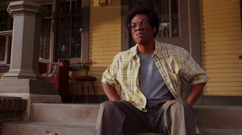 Movie still from “Norbit” (2007), directed by Brian Robbins – A man sitting on the steps of a house; Medium shot, Low angle