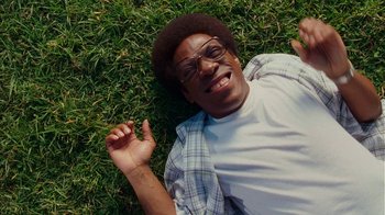 Movie still from “Norbit” (2007), directed by Brian Robbins – A man laying in the grass smiling for the camera; Close Up shot, Overhead angle
