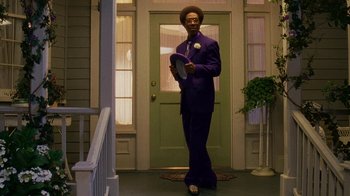 Movie still from “Norbit” (2007), directed by Brian Robbins – A man in a purple suit standing in front of a green door; Medium shot, Low angle