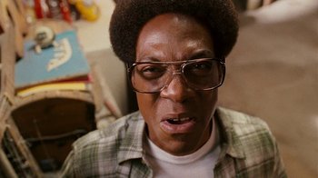 Movie still from “Norbit” (2007), directed by Brian Robbins – A person wearing glasses and a plaid shirt; Close Up shot, Low angle