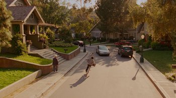Movie still from “Norbit” (2007), directed by Brian Robbins – A man riding a skateboard down the side of a street; Extreme Wide shot, High angle