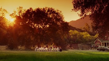 Movie still from “Norbit” (2007), directed by Brian Robbins – A group of people sitting around a table in a field; Extreme Wide shot, High angle