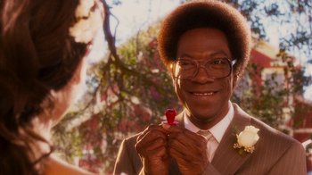 Movie still from “Norbit” (2007), directed by Brian Robbins – A man in a suit and tie holding a flower; Close Up shot, Over the shoulder angle
