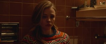 Movie still from “Mother/Android” (2021), directed by Mattson Tomlin – A girl with long hair wearing a colorful sweater; Close Up shot, Over the shoulder angle