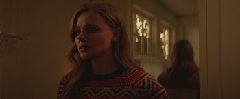 Movie still from “Mother/Android” (2021), directed by Mattson Tomlin – A woman with long blonde hair wearing a colorful sweater; Close Up shot, Over the shoulder angle