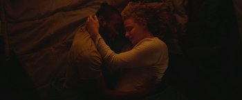 Movie still from “Mother/Android” (2021), directed by Mattson Tomlin – A man and a woman laying in bed together; Medium shot, Overhead angle