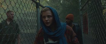 Movie still from “Mother/Android” (2021), directed by Mattson Tomlin – A woman with a blue head scarf standing in front of a fence; Close Up shot, Low angle