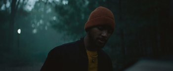 Movie still from “Mother/Android” (2021), directed by Mattson Tomlin – A man wearing a hat and a yellow shirt; Close Up shot, Low angle