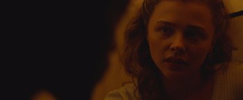 Movie still from “Mother/Android” (2021), directed by Mattson Tomlin – A woman's face in a dark room; Close Up shot, Over the shoulder angle