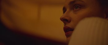 Movie still from “Mother/Android” (2021), directed by Mattson Tomlin – A person's face in a dimly - lit room; Extreme Close Up shot, Low angle