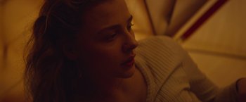 Movie still from “Mother/Android” (2021), directed by Mattson Tomlin – A person sitting on a couch; Close Up shot, High angle