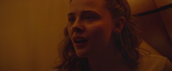 Movie still from “Mother/Android” (2021), directed by Mattson Tomlin – A young woman with long red hair is looking at the camera; Close Up shot, Over the shoulder angle