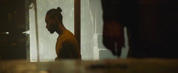 Movie still from “Mother/Android” (2021), directed by Mattson Tomlin – A man sitting in front of a window with his hand on his head; Close Up shot, Over the shoulder angle