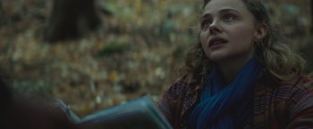 Movie still from “Mother/Android” (2021), directed by Mattson Tomlin – A woman is looking up while holding a book in her hand; Close Up shot, Low angle