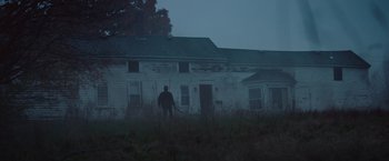 Movie still from “Mother/Android” (2021), directed by Mattson Tomlin – A man standing in front of a house in the dark; Extreme Wide shot, Low angle