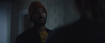 Movie still from “Mother/Android” (2021), directed by Mattson Tomlin – A man wearing a yellow shirt and a brown hat; Close Up shot, Over the shoulder angle