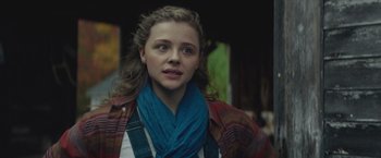 Movie still from “Mother/Android” (2021), directed by Mattson Tomlin – A young woman wearing a blue scarf and a plaid jacket; Close Up shot, Over the shoulder angle