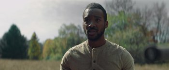 Movie still from “Mother/Android” (2021), directed by Mattson Tomlin – A person wearing a shirt with trees in the background; Close Up shot, Over the shoulder angle