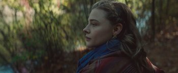 Movie still from “Mother/Android” (2021), directed by Mattson Tomlin – A young woman with long brown hair wearing a blue scarf; Close Up shot, Over the shoulder angle