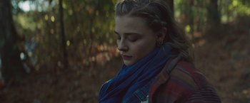 Movie still from “Mother/Android” (2021), directed by Mattson Tomlin – A woman wearing a blue scarf is looking down at the ground; Close Up shot, Over the shoulder angle