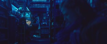 Movie still from “Mother/Android” (2021), directed by Mattson Tomlin – Two people sitting at a table in a dark room; Wide shot, Over the shoulder angle