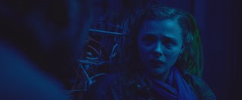 Movie still from “Mother/Android” (2021), directed by Mattson Tomlin – A woman in a dark room looking at the camera; Close Up shot, Over the shoulder angle