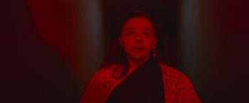 Movie still from “Mother/Android” (2021), directed by Mattson Tomlin – A woman in a black shirt and a red polka dot scarf; Close Up shot, Low angle