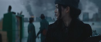 Movie still from “Mother/Android” (2021), directed by Mattson Tomlin – A woman in a black coat and a hat looking off into the distance; Close Up shot, Over the shoulder angle