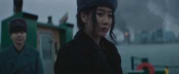 Movie still from “Mother/Android” (2021), directed by Mattson Tomlin – A woman wearing a black coat and a hat; Close Up shot, Over the shoulder angle