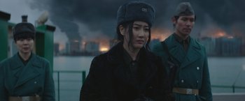 Movie still from “Mother/Android” (2021), directed by Mattson Tomlin – A woman wearing a black coat and a hat; Medium shot, Over the shoulder angle