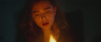 Movie still from “Mother/Android” (2021), directed by Mattson Tomlin – A woman is holding a candle in a dark room; Close Up shot, Low angle