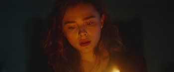 Movie still from “Mother/Android” (2021), directed by Mattson Tomlin – A woman with a candle in a dark room; Close Up shot, High angle