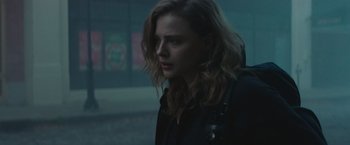 Movie still from “Mother/Android” (2021), directed by Mattson Tomlin – A woman with long hair is standing in the dark; Close Up shot, Over the shoulder angle