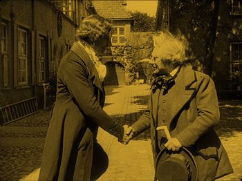 Movie still from “Nosferatu” (1922), directed by F.W. Murnau – Two people are shaking hands on the sidewalk; Medium shot, High angle