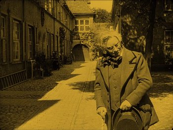 Movie still from “Nosferatu” (1922), directed by F.W. Murnau – An old man walking down the street with a hat on; Wide shot, High angle