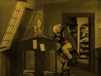 Movie still from “Nosferatu” (1922), directed by F.W. Murnau – An old man sitting at a desk writing on a paper; Wide shot, High angle