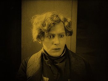 Movie still from “Nosferatu” (1922), directed by F.W. Murnau – An old photo of a young man with curly brown hair; Medium shot, High angle