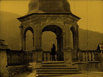 Movie still from “Nosferatu” (1922), directed by F.W. Murnau – A person standing in front of a gazebo with steps; Wide shot, High angle