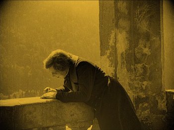 Movie still from “Nosferatu” (1922), directed by F.W. Murnau – A man leaning on a wall writing on a piece of paper; Wide shot, High angle