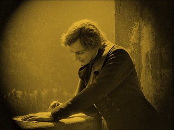 Movie still from “Nosferatu” (1922), directed by F.W. Murnau – A person writing on a piece of paper; Medium shot, High angle