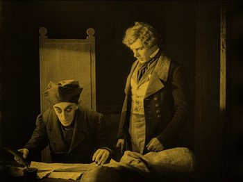 Movie still from “Nosferatu” (1922), directed by F.W. Murnau – Two men are sitting at a table looking at papers; Medium shot, High angle