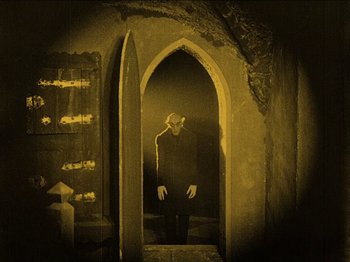 Movie still from “Nosferatu” (1922), directed by F.W. Murnau – A man standing in an archway in a dark room; Wide shot, High angle