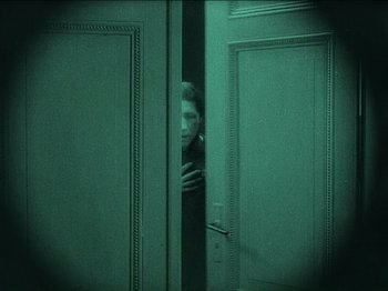 Movie still from “Nosferatu” (1922), directed by F.W. Murnau – A man peeks out from behind two doors; Medium shot, High angle