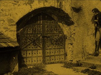 Movie still from “Nosferatu” (1922), directed by F.W. Murnau – An old picture of an open door to an old building; Extreme Wide shot, High angle