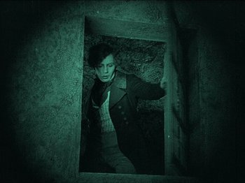 Movie still from “Nosferatu” (1922), directed by F.W. Murnau – A man standing inside of an open doorway; Medium shot, High angle